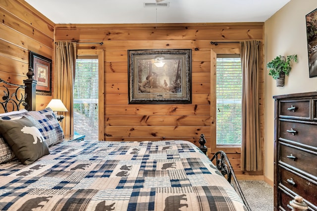 carpeted bedroom featuring wooden walls