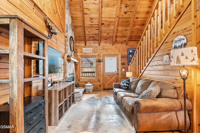 living area with wooden walls, wood finished floors, lofted ceiling with beams, stairs, and wooden ceiling