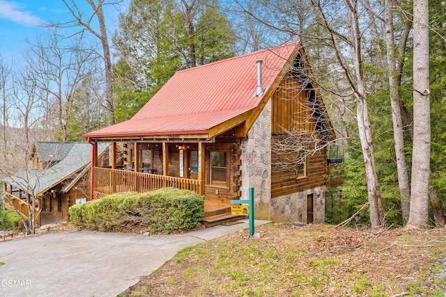 view of front facade with covered porch, log exterior, and metal roof