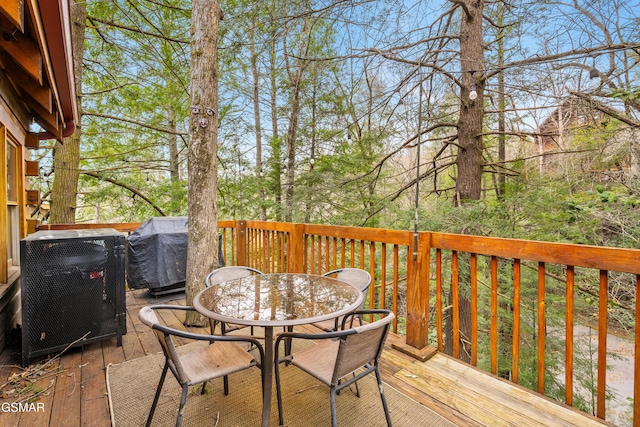 wooden deck featuring outdoor dining area, cooling unit, and grilling area