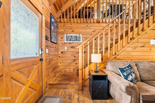 staircase featuring wood finished floors, wood walls, and vaulted ceiling