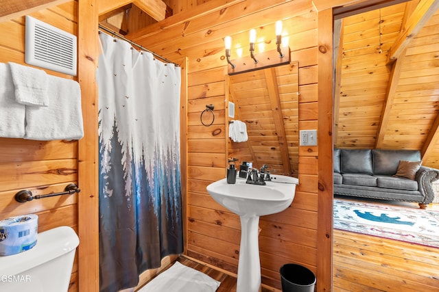 full bathroom featuring a shower with shower curtain, wooden walls, beam ceiling, wooden ceiling, and toilet