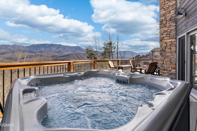 wooden deck with a mountain view and a hot tub