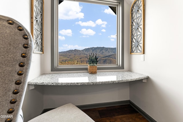 interior details featuring built in study area, a mountain view, baseboards, and wood finished floors