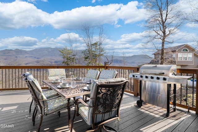 wooden deck with outdoor dining area, area for grilling, and a mountain view