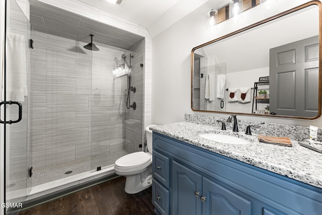 full bath with toilet, a shower stall, wood finished floors, and vanity