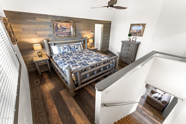 bedroom with wood-type flooring, wooden walls, vaulted ceiling, and a ceiling fan