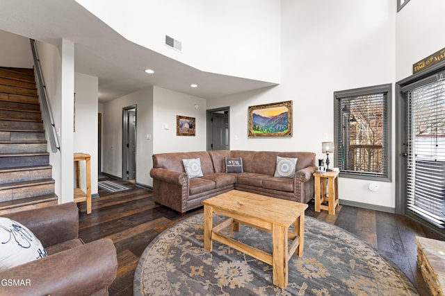 living area featuring wood-type flooring, visible vents, baseboards, and stairs