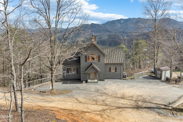 rustic home with driveway, metal roof, a chimney, and a mountain view