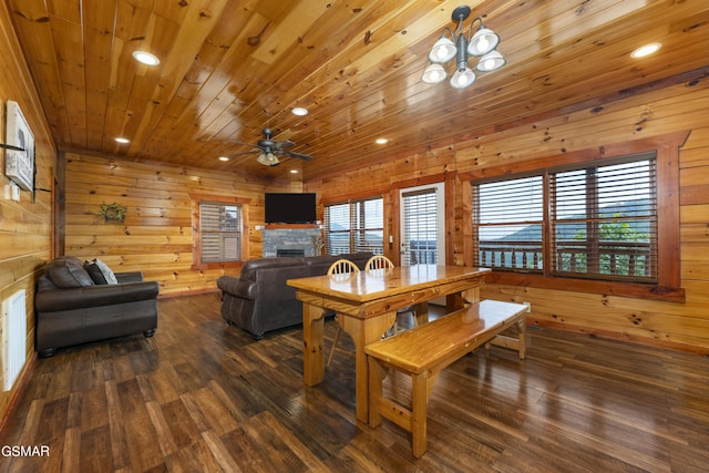 dining space featuring ceiling fan, wooden ceiling, a fireplace, and wooden walls