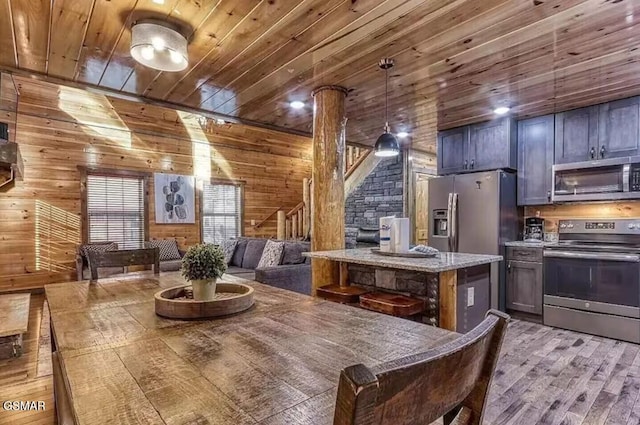 dining space with wood finished floors, wooden walls, wooden ceiling, decorative columns, and stairs