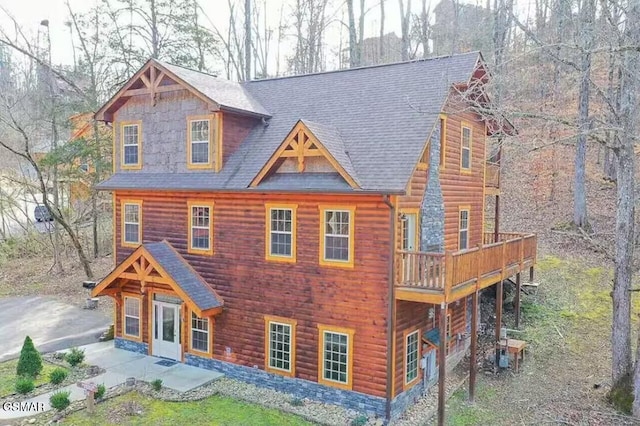 view of front facade with a shingled roof and a patio