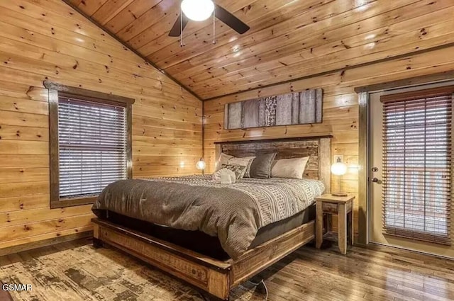 bedroom featuring multiple windows, hardwood / wood-style flooring, wood walls, wooden ceiling, and vaulted ceiling