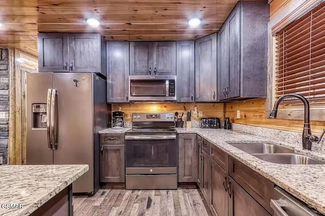 kitchen featuring light stone counters, recessed lighting, a sink, stainless steel appliances, and light wood-style floors