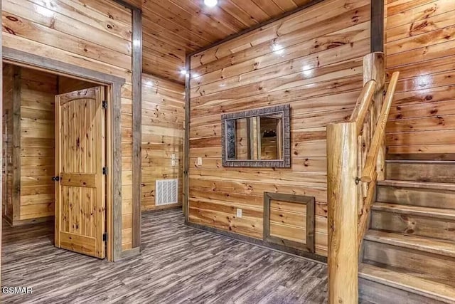 empty room featuring stairway, wood finished floors, wooden ceiling, and wood walls