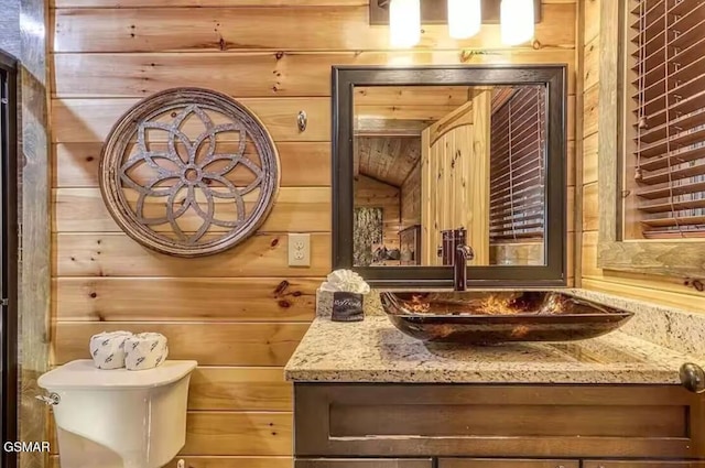 half bathroom with wooden walls, vanity, and toilet