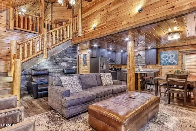 living area featuring wood finished floors, wood walls, wooden ceiling, a towering ceiling, and stairs