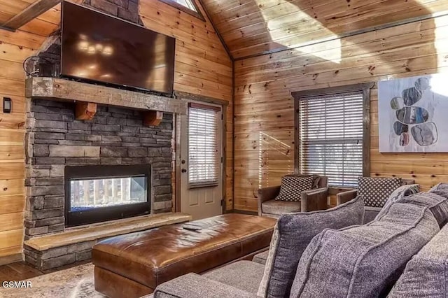 living room featuring wood finished floors, wooden walls, a fireplace, and a wealth of natural light