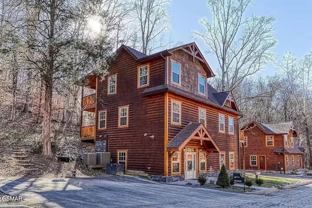 view of front of property featuring stone siding and a balcony