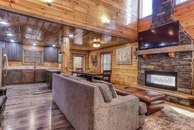 living area with a stone fireplace, wooden walls, wood ceiling, and hardwood / wood-style floors