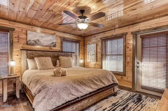 bedroom with access to exterior, wood finished floors, wooden walls, wooden ceiling, and ceiling fan