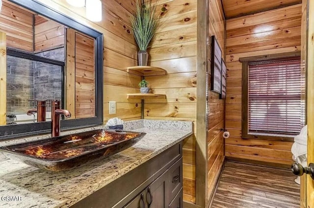 bathroom with vanity, wood finished floors, and wood walls