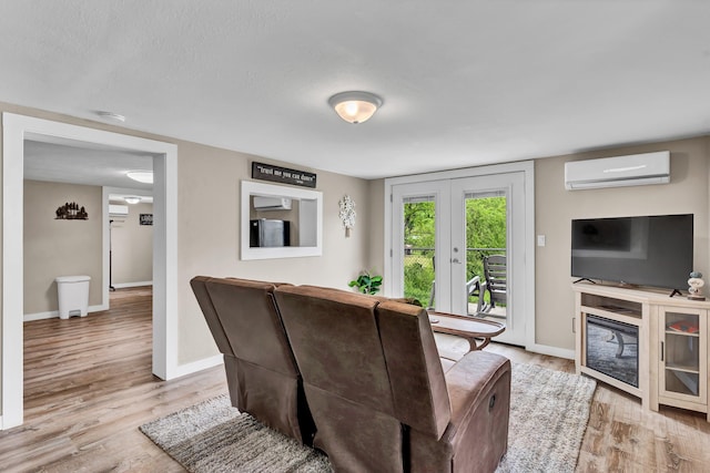 living room with a wall mounted air conditioner, french doors, and light hardwood / wood-style flooring