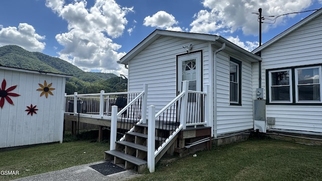 property entrance featuring a deck with mountain view and a lawn