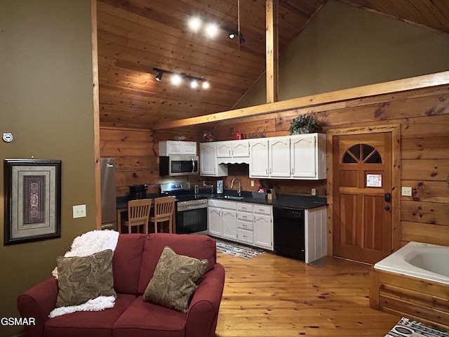 kitchen featuring light wood-type flooring, white cabinets, dark countertops, a sink, and stainless steel appliances