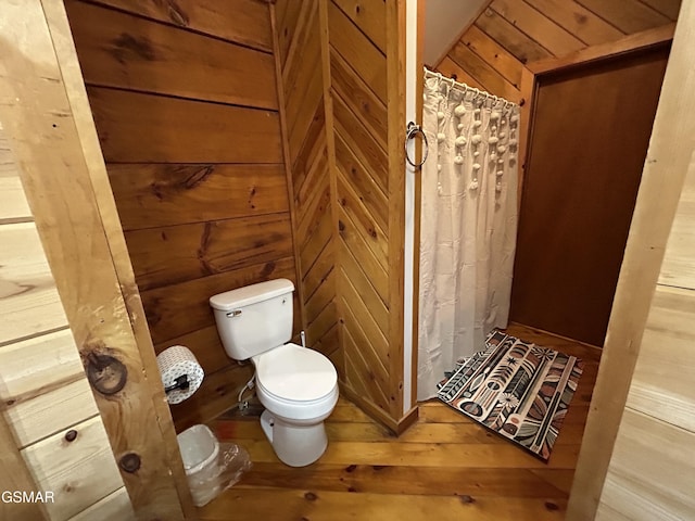 bathroom featuring wood walls, toilet, hardwood / wood-style floors, and a shower with curtain