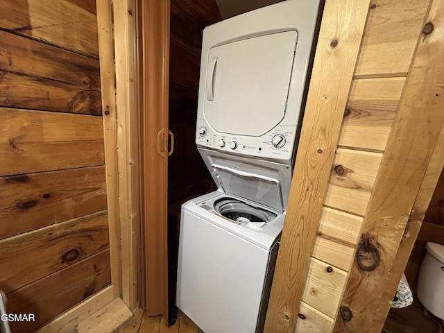 washroom featuring laundry area, stacked washer and clothes dryer, and wooden walls