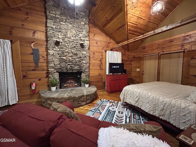 bedroom with a stone fireplace, wood ceiling, wooden walls, vaulted ceiling, and wood finished floors
