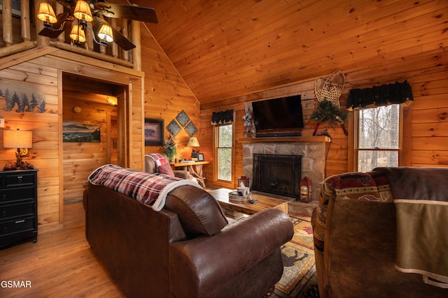 living room with a fireplace, a healthy amount of sunlight, wooden walls, and light hardwood / wood-style flooring