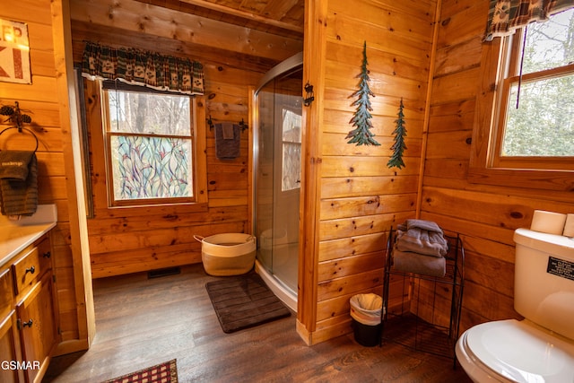 bathroom with wood-type flooring, wooden walls, a shower with shower door, and vanity