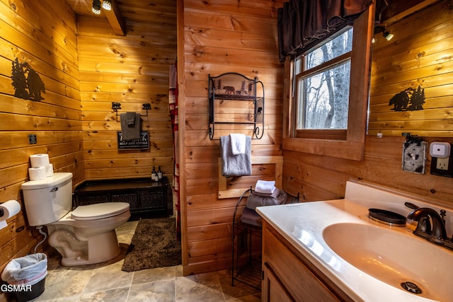 bathroom with vanity, wooden walls, and toilet