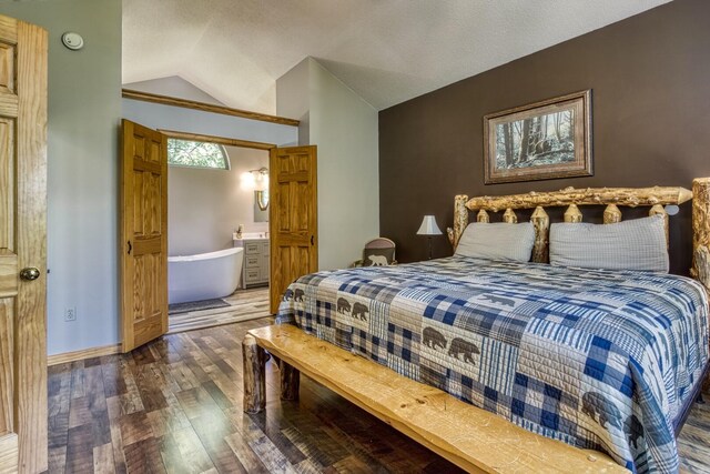 bedroom with connected bathroom, dark hardwood / wood-style flooring, and lofted ceiling