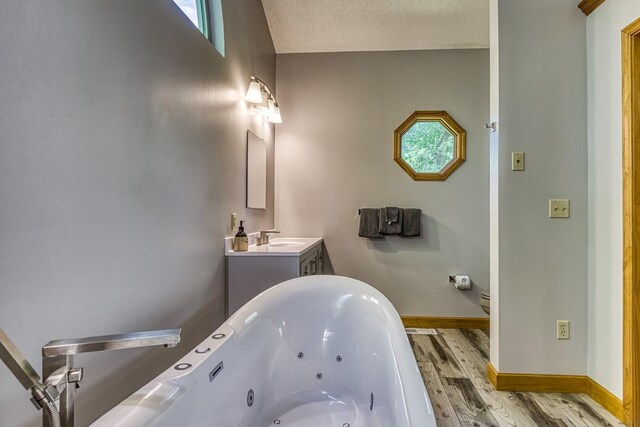 bathroom with vanity, hardwood / wood-style flooring, toilet, a textured ceiling, and a tub