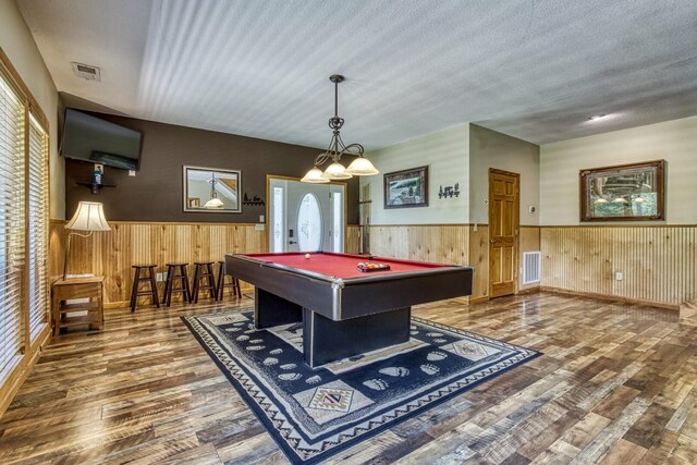 game room with a textured ceiling, hardwood / wood-style flooring, a wealth of natural light, and billiards