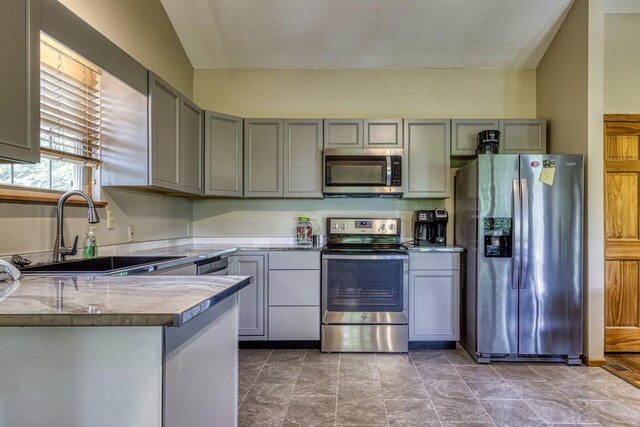 kitchen with gray cabinetry, sink, stainless steel appliances, and a textured ceiling