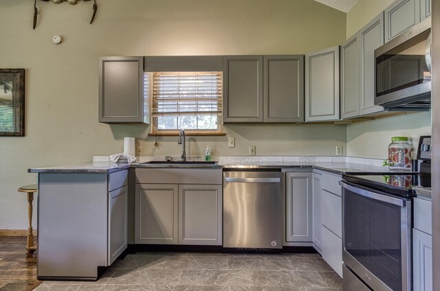 kitchen featuring kitchen peninsula, appliances with stainless steel finishes, gray cabinets, and sink