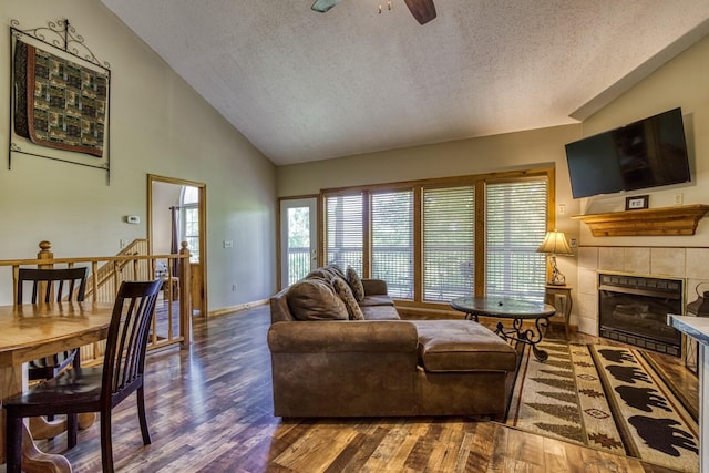 living room with a fireplace, a textured ceiling, dark hardwood / wood-style flooring, and ceiling fan