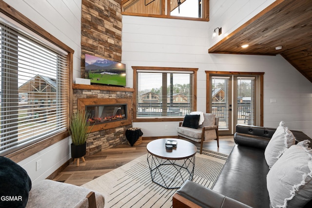 living area with high vaulted ceiling, a fireplace, wood finished floors, and wooden walls