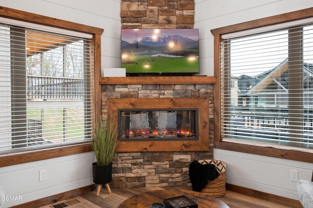 room details featuring wood walls, visible vents, wood finished floors, and a stone fireplace