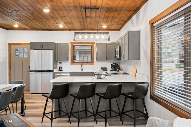 kitchen featuring light countertops, appliances with stainless steel finishes, hanging light fixtures, and wood ceiling