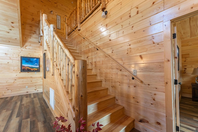 staircase with wooden walls and wood-type flooring