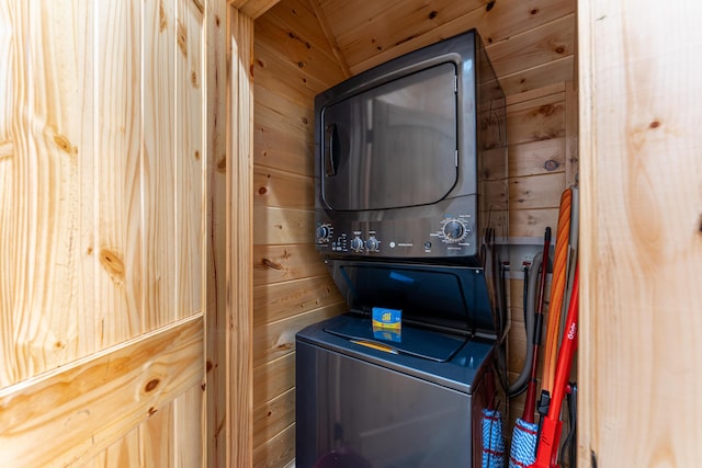 laundry area featuring stacked washer / dryer and wood walls