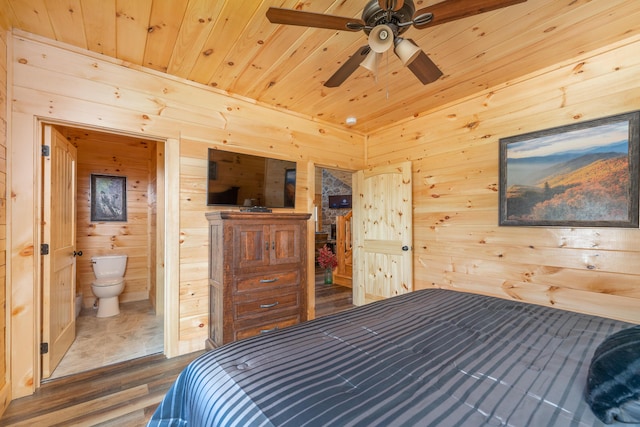 bedroom featuring connected bathroom, ceiling fan, wood-type flooring, and wood walls