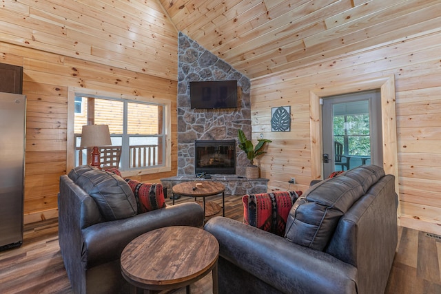 living room featuring wooden walls, wood-type flooring, high vaulted ceiling, wooden ceiling, and a stone fireplace