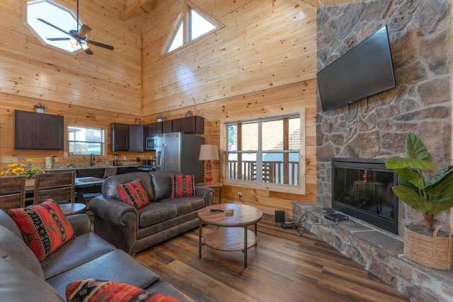 living room with hardwood / wood-style flooring, high vaulted ceiling, plenty of natural light, and wood walls