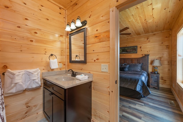 bathroom featuring wood ceiling, vanity, ceiling fan, wooden walls, and wood-type flooring